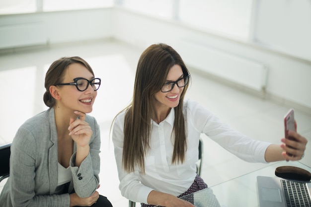 Colegas de trabalho tiram selfies sentados na mesa