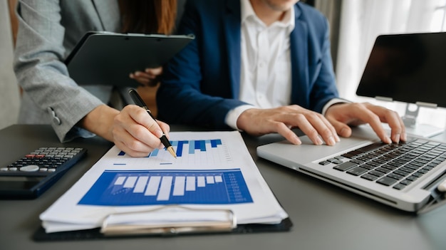 Colegas de trabalho trabalhando juntos discutem e usam tablet e laptop no escritório com documento financeiro no deskxA