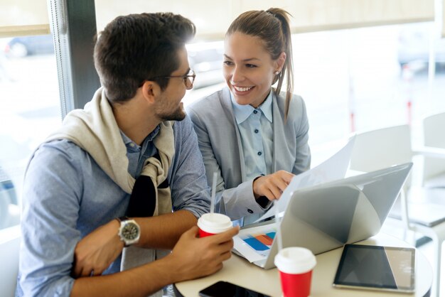 Colegas de trabalho trabalhando no projeto enquanto está sentado no café. no laptop de mesa, tablet e copos descartáveis com café.