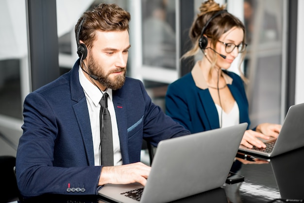 Colegas de trabalho vestidos de ternos para a conferência oline com fone de ouvido e laptop sentados no escritório