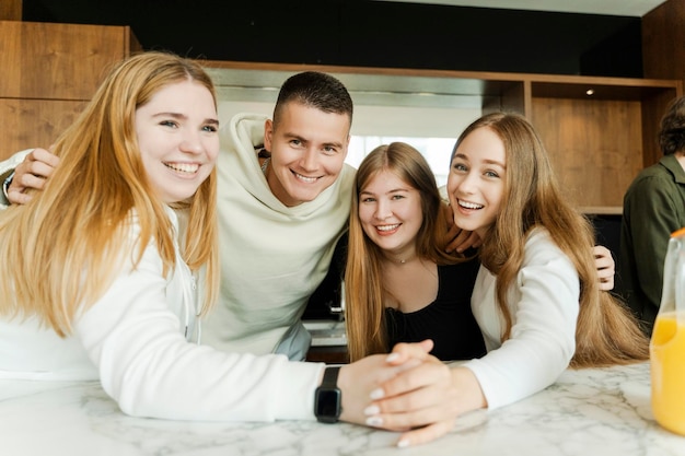 Colegas despreocupados, jovens felizes, homens e mulheres olhando para a câmera, abraçando-se, divertindo-se em casa, pessoas conversando, passando o fim de semana juntos, conceito de festa em casa.