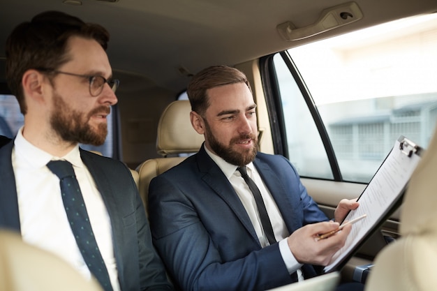 Colegas discutiendo contrato en el auto