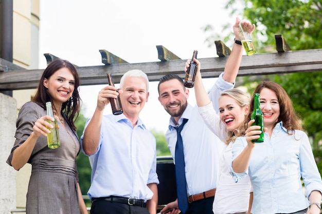 Colegas do escritório bebendo cerveja depois do trabalho no terraço comemorando