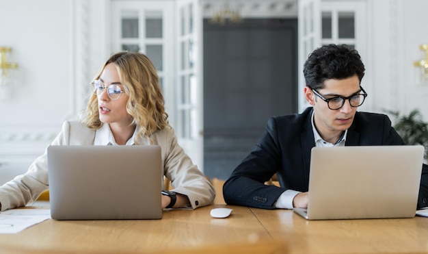 Foto colegas do sexo masculino e feminino trabalham no escritório e usam laptops no local de trabalho empreendedores