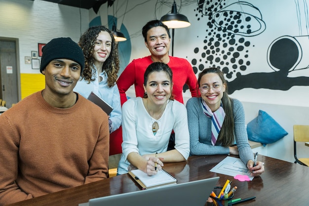 Colegas em um espaço de coworking sorriem para a câmera trabalhando juntos como uma equipe