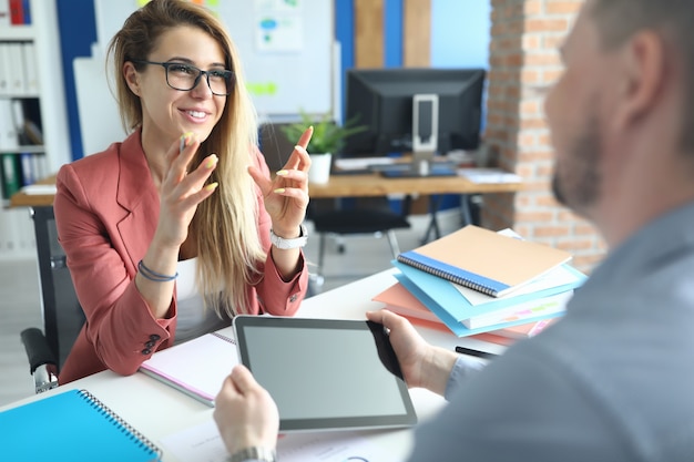 Colegas estão sentados à mesa no escritório conversando e sorrindo. Discussão do conceito de project finance