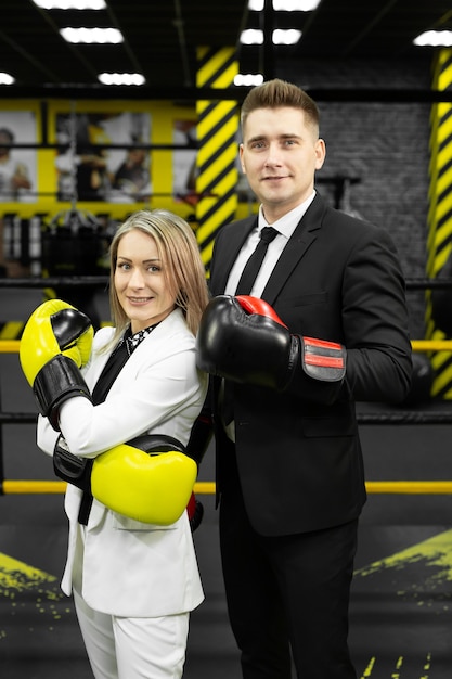 Colegas, un hombre y una mujer en traje y guantes de boxeo en el ring.