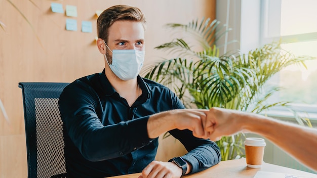 Foto los colegas con máscaras médicas evitan estrechar la mano cuando se reúnen en la oficina virus nuevo concepto de realidad