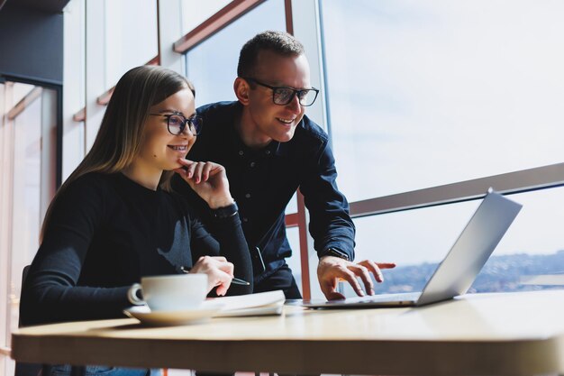 Colegas masculinos e femininos da equipe de negócios bem-sucedidos conversando no trabalho discutindo um novo projeto com um laptop jovens executivos têm uma conversa amigável cooperar no trabalho em equipe no escritório