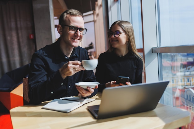 Colegas masculinos e femininos da equipe de negócios bem-sucedidos conversando no trabalho discutindo um novo projeto com um laptop jovens executivos têm uma conversa amigável cooperar no trabalho em equipe no escritório