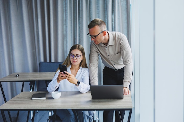 Colegas masculinos y femeninos intercambian ideas sobre la información del proyecto en formato en línea durante el tiempo de trabajo en la oficina en una computadora portátil jóvenes socios exitosos que leen noticias y comparten ideas en netbook