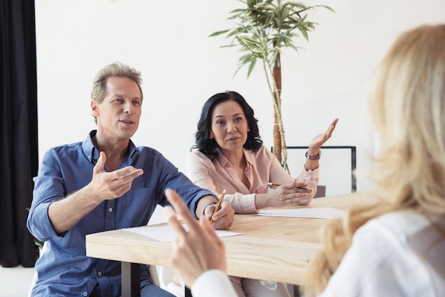 Foto colegas de mediana edad disputando en una reunión de negocios en la oficina