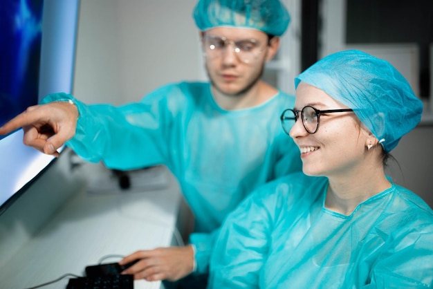 Los colegas médicos jóvenes trabajan y estudian en la computadora Los cirujanos masculinos y femeninos en uniforme son stu