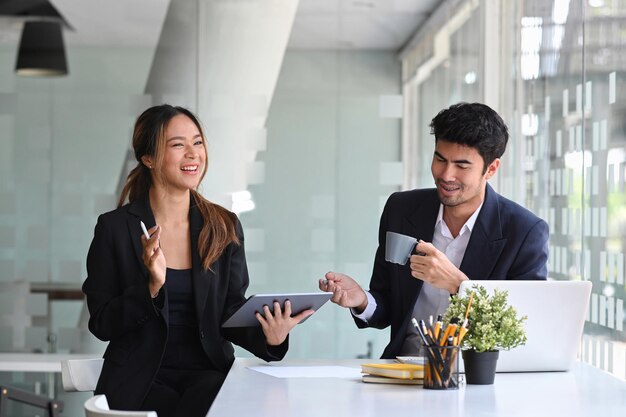 Colegas de negocios felices sentados juntos en una oficina moderna y discutiendo ideas de proyectos