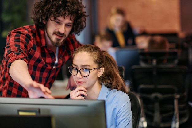 Colegas de negocios un hombre y una mujer se involucran en la discusión de estrategias comerciales mientras miran atentamente un monitor de computadora que personifica la colaboración y la innovación