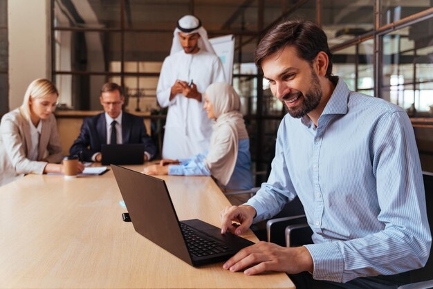 Colegas de negocios usando la computadora portátil mientras están sentados en la mesa