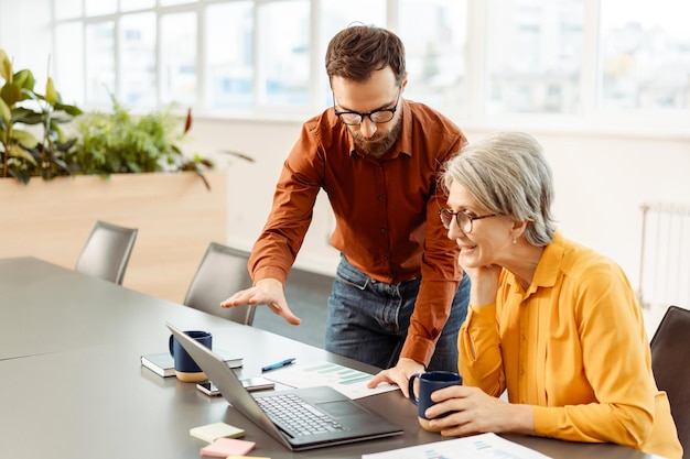 Foto colegas de negocios usando portátiles hablando compartiendo ideas planeando una startup bebiendo café