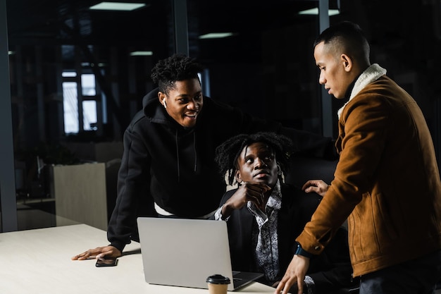 Colegas negros e asiáticos trabalhando juntos em laptops em equipe multiétnica e discutindo projeto de trabalho on-line