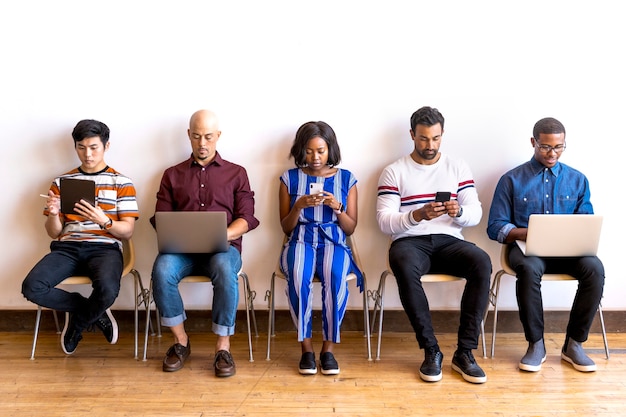 Colegas sentados em uma fila usando dispositivos digitais