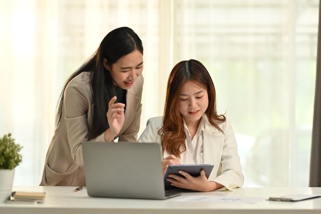 Colegas sonrientes y exitosos que utilizan la planificación de tabletas digitales inician proyectos compartiendo ideas en el espacio de trabajo conjunto