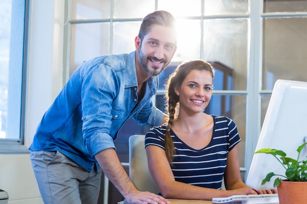 Colegas sorridentes trabalhando juntos no computador