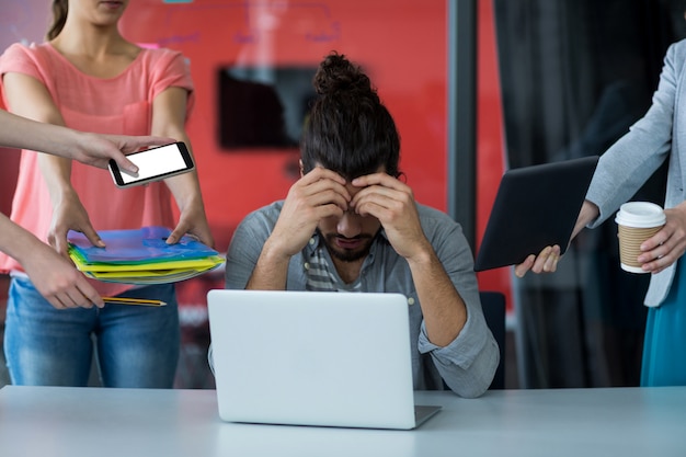 Colegas con tableta digital y teléfono móvil hablando con hombre frustrado