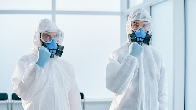 Colegas en trajes de riesgo biológico de pie en el laboratorio