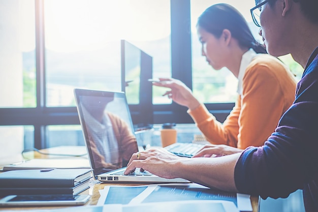 Colegas usando computadora portátil en el escritorio en la oficina