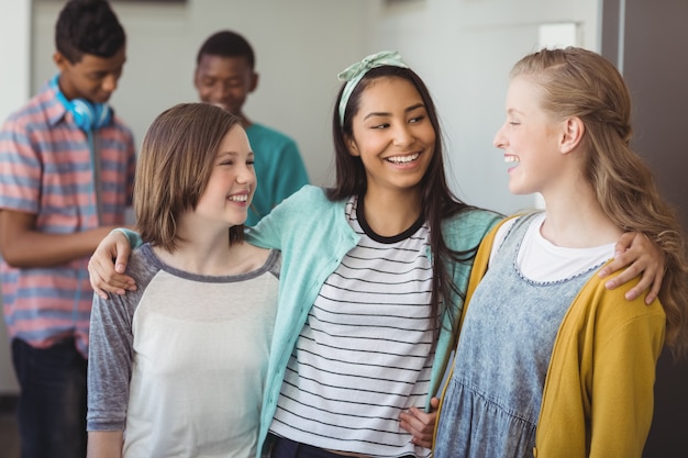 Colegiais sorridentes em pé e com os braços no corredor