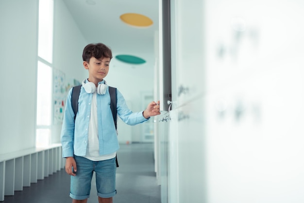 Colegial abriendo su casillero escolar durante las vacaciones escolares