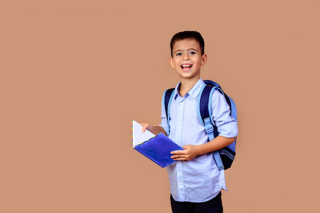 Colegial alegre niño feliz con libros en las manos y mochila