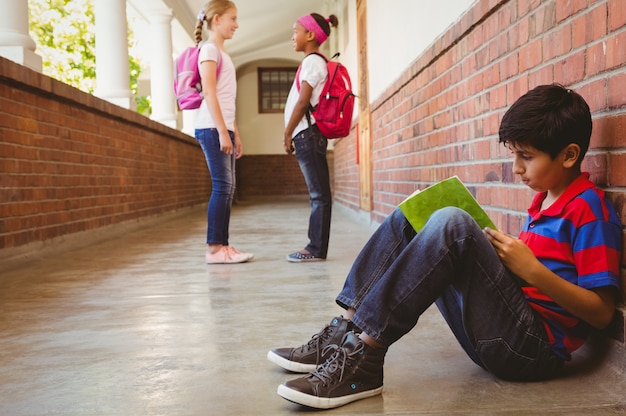 Colegial con amigos en segundo plano en el pasillo de la escuela