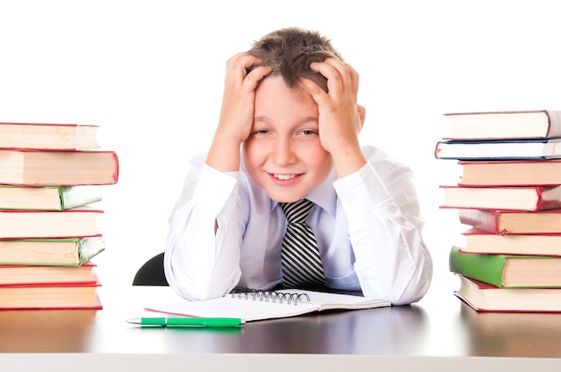 Un colegial cansado y rezagado se sienta en una biblioteca con libros y aprende lecciones. Falta de voluntad para aprender.