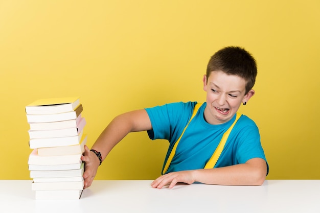 Colegial con cara desagradable rechazando pila de libros