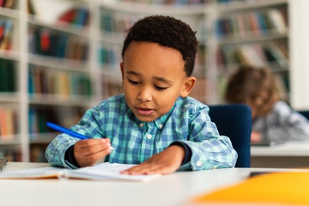 Un colegial centrado escribiendo en un cuaderno durante la lección en el aula