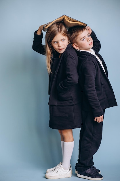 Colegial y colegiala vistiendo uniforme y sosteniendo libros