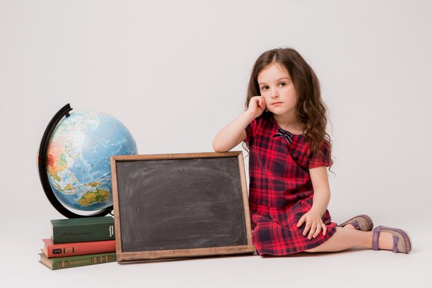 Colegial com globo, livros e prancheta em branco sobre fundo branco