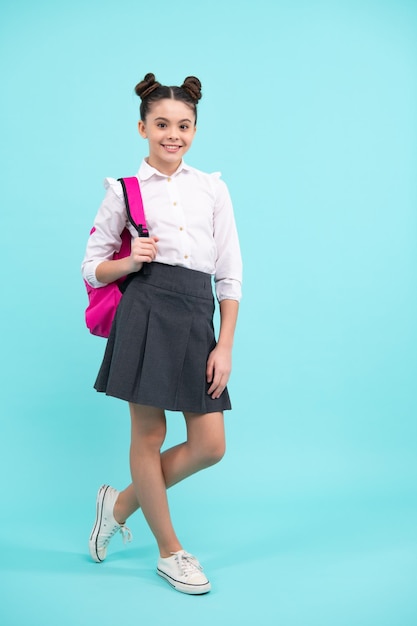 Colegial em uniforme escolar com mochila escolar Estudante adolescente em fundo azul isolado