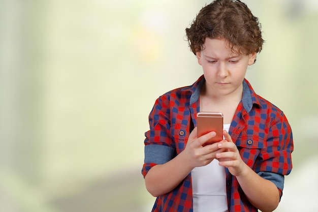 El colegial enviando un mensaje desde el teléfono móvil aislado