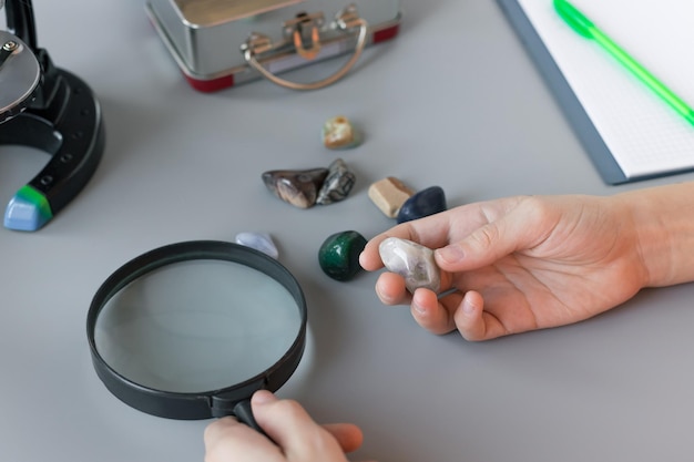 El colegial estudiando piedras semipreciosas en el escritorio gris en el hogar Concepto de científicos de educación