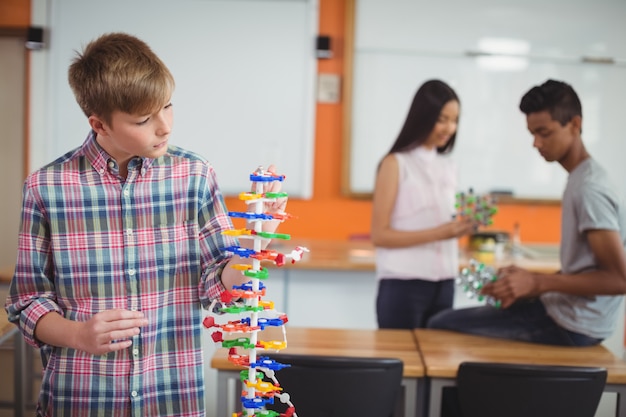 El colegial examina el modelo de la molécula en el laboratorio