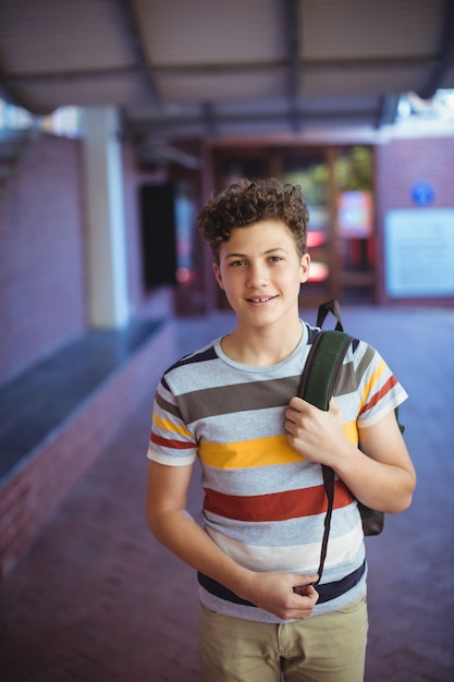 Colegial feliz de pie en el campus de la escuela