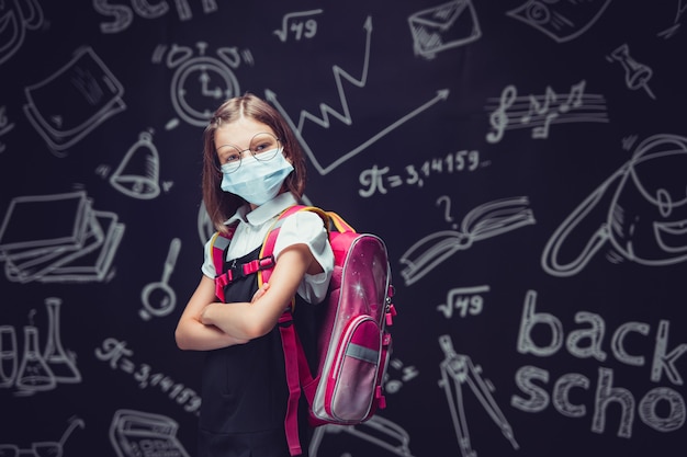 Colegial furiosa com máscara de proteção se prepara para ir para a escola proteção contra vírus para crianças