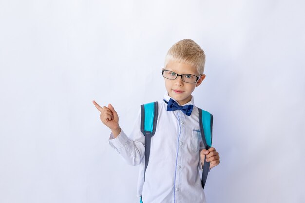 El colegial de gafas y una camisa blanca apunta hacia arriba