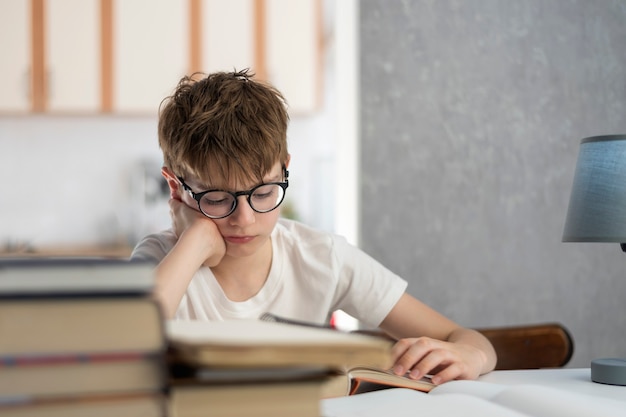 El colegial hace su tarea. El niño lee el libro de texto. La educación a distancia. Educación en el hogar. Harry Potter moderno.