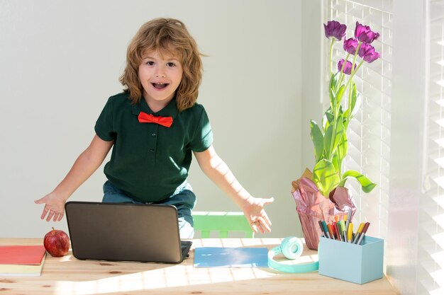 Colegial haciendo la tarea niño divertido aprende con la computadora portátil en la sala de estudio