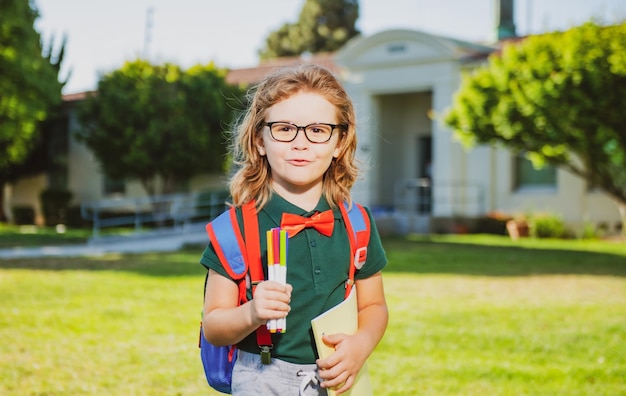 Colegial inteligente en gafas con mochila escolar y libro en la mano retrato de alumnos de regreso a la escuela en s