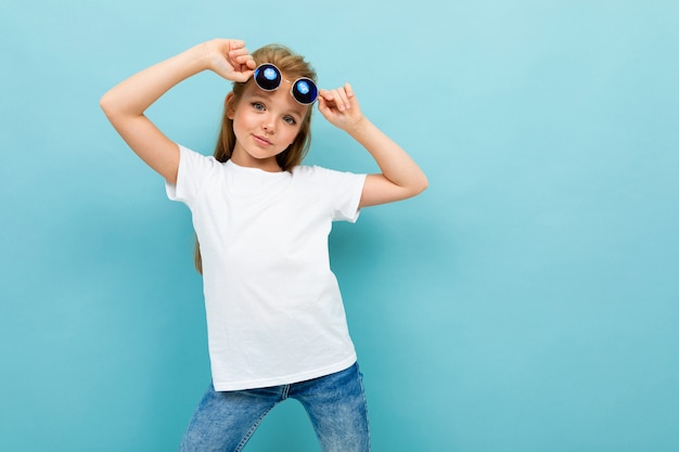 Foto colegial linda elegante em uma camisa branca sobre um fundo azul posando