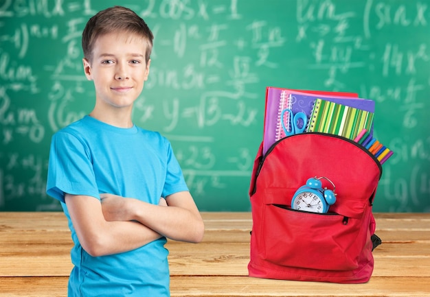 Colegial con las manos cruzadas y mochila sonriendo a la cámara