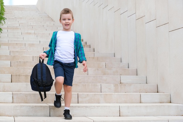 Colegial con una mochila en la mano en la calle camino a la escuela baja las escaleras Regreso a la escuela